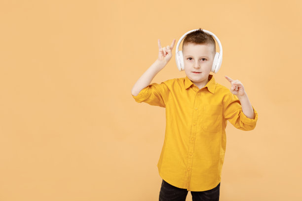 滑稽聪明的学生肖像，戴着耳机，黄色衬衫。黄色工作室背景。教育。看着镜头微笑图片下载
