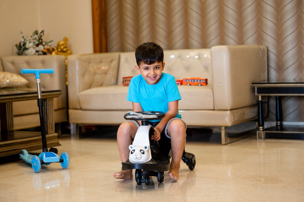 快乐的孩子在家里骑着他的摇摆车或滑板车。图片下载