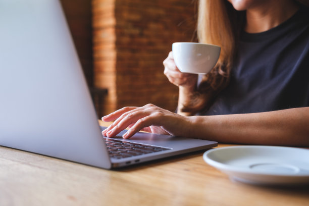 一名女商人一边喝咖啡，一边在笔记本电脑上工作的特写图像图片下载