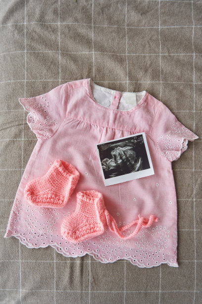 为一个穿着粉色裙子的新生儿织的靴子，旁边还有一张超声波扫描图图片下载