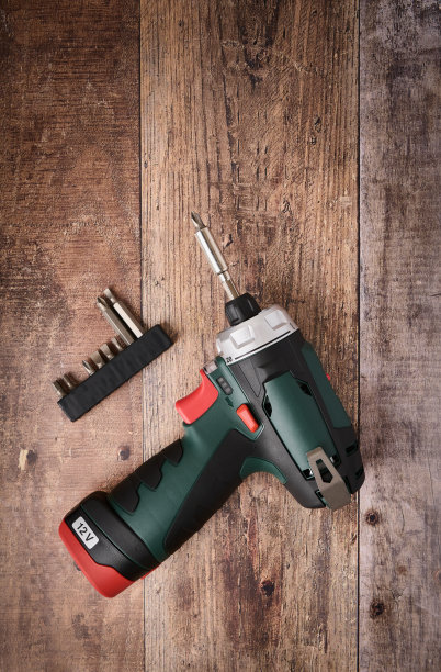 无绳螺丝起子钻和钻头放置在木桌上，专业工具图片下载