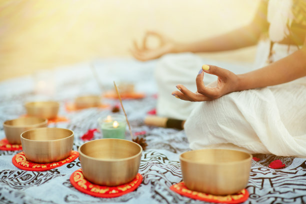 瑜伽冥想与西藏唱碗音乐。慕德拉双手放在膝盖上的特写。女人在阳光下冥想和放松。放松声音疗法和精神治疗的概念。图片下载