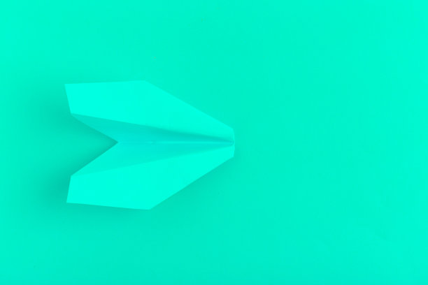 在绿色粉彩背景上的平面纸飞机图片下载