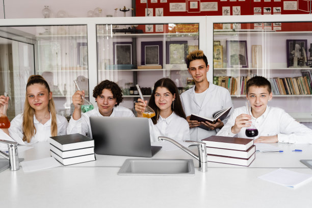 在实验室的化学课上，同学朋友们兴高采烈地捧着装有彩色液体的试管。学校教育。师生之间的交流。图片下载