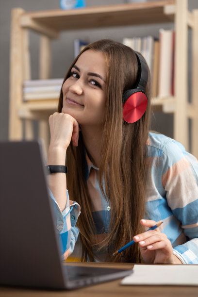 女孩放松地听音乐，戴着耳机，思考孤独的想法。女学生在线学习图片下载