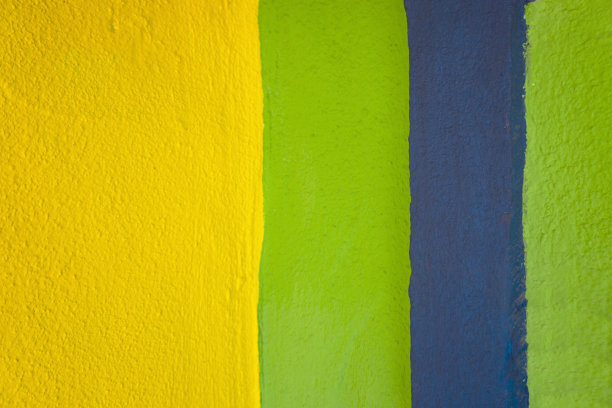 在混凝土墙上涂上黄色、蓝色和绿色的油漆。图片下载