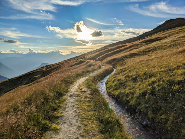 旁边有条山间小溪的徒步小道。在韦尔比耶附近的瓦莱州阿尔卑斯山，美丽的夜晚气氛。高质量的照片图片下载