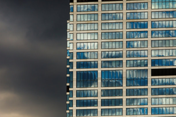 镜像办公建筑的窗户与戏剧性的云背景。图片下载