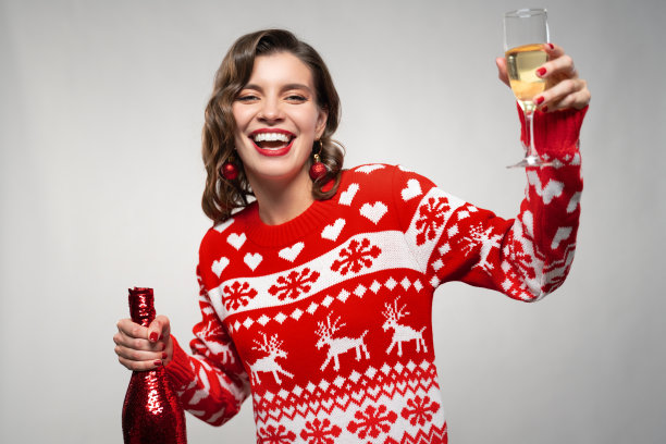 穿着毛衣的女人举起香槟祝你圣诞快乐的肖像图片下载