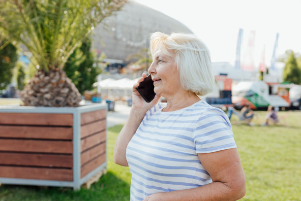 漂亮成熟的女人在时髦的穿着花时间在街上使用智能手机。开心学长煲手机粥，温暖晴天。城市生活理念，科技旗帜图片下载