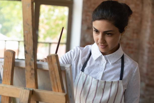 迷人的印度女画家拿着画笔在画布上画画图片下载