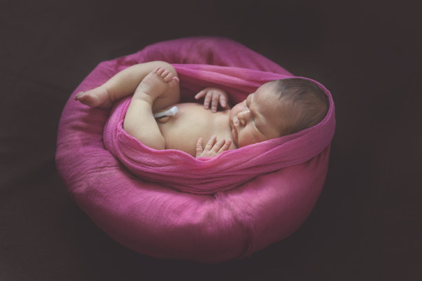 娇嫩的新生儿裹着粉红色的围巾睡觉图片下载