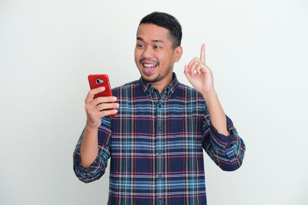 亚洲成年男子看他的手机与快乐的表情图片下载