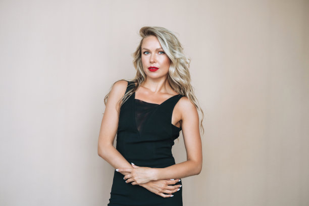 华丽美丽的金发年轻女子的肖像与明亮的化妆在晚礼服上的米色背景图片下载