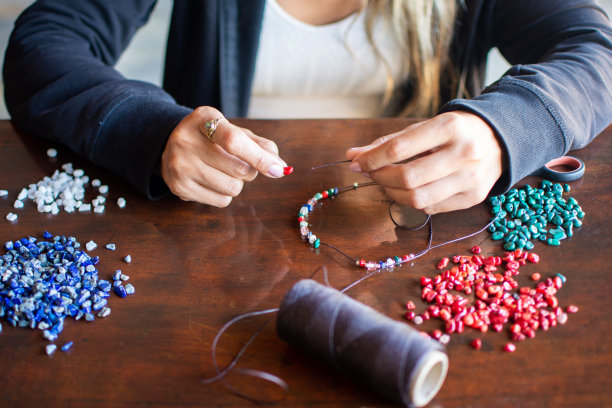 女性手制作手工项链与蓝色，红色，绿色和白色的石头图片下载