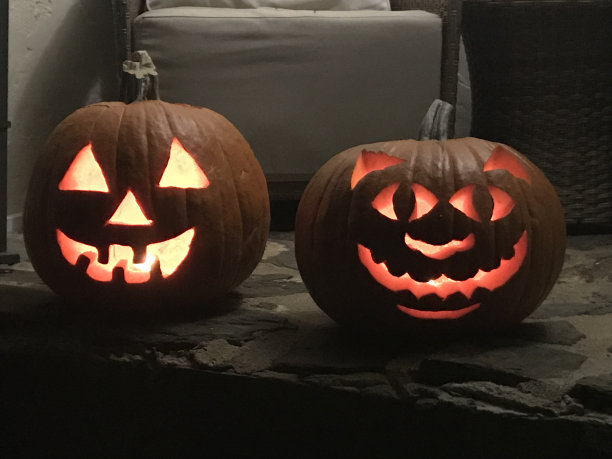 两根蜡烛点燃万圣节杰克灯南瓜坐在门廊上图片下载