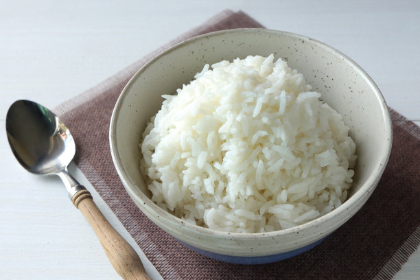 白米饭在黑色的碗，白色的木制背景。白碗蒸饭。俯视图图片下载