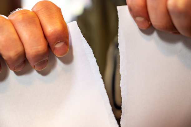 两只手从上到下撕一张白纸。图片下载