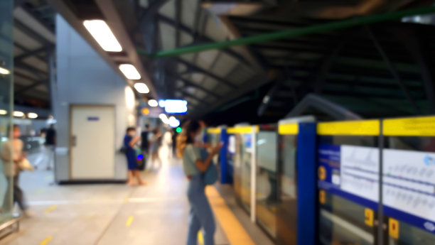 模糊的影像在夜间的捷运火车站，亚洲人在晚上等待电动地铁列车。捷运是泰国曼谷的一种公共交通工具。图片下载