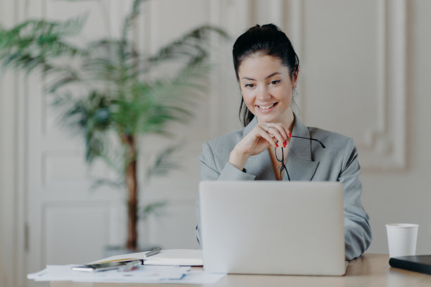 开朗的年轻职业女性搜索笔记本电脑更新通知，摘下眼镜，穿着正装办公室内。自由职业者远程搜索博客网站的想法图片下载