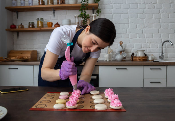 糕点师把奶油从糕点袋里挤到马卡龙上。有选择性的重点。关于甜点、食物的网站照片。图片下载