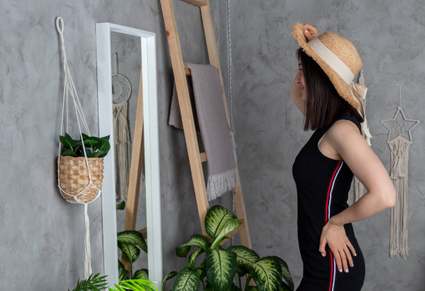 戴帽子的年轻女子在镜子里审视自己。有选择性的重点。图片网站关于衣服，女人。图片下载