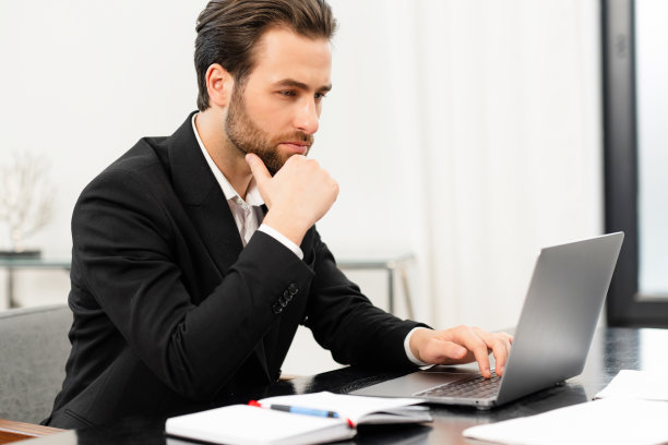 英俊专注的年轻商人，穿着正装，使用笔记本电脑图片下载