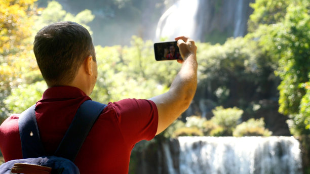 年轻成功的博主或视频博主在户外用智能手机自拍视频，看相机，谈论电影，在自然中用手机拍摄博客。社交媒体影响者，内容制造者的概念图片下载