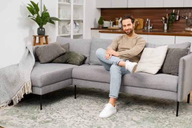 年轻白人男子躺在沙发上的肖像。英俊积极的男人坐在客厅的沙发上，做白日梦，放松身心图片下载