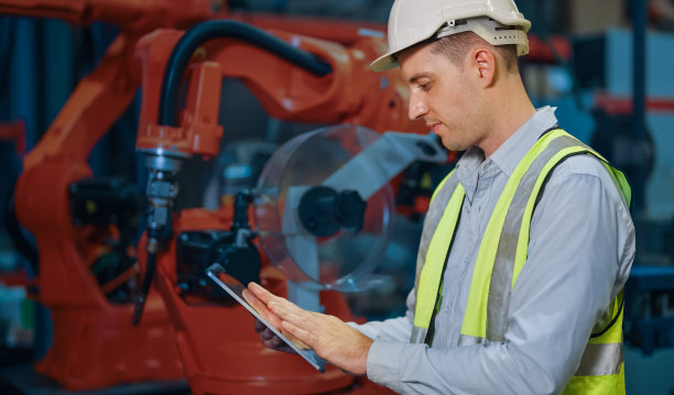 可编程机器人控制器，可编程机械臂。生产线上的机械臂。在工厂使用笔记本电脑检查机的工程师。工程师编码机器人。图片下载
