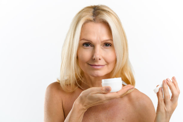 迷人的中年金发碧眼的40多岁的女人拿着一瓶抗衰老保湿霜，看着相机孤立在白色背景，复制空间图片下载