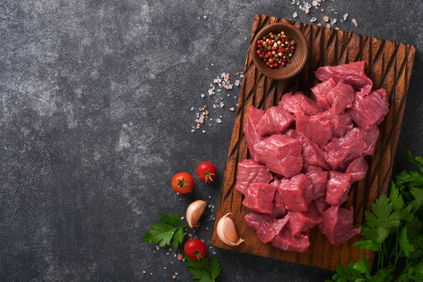 生牛肉碎。生的有机肉牛肉或羊肉，香料，香草在旧木板上深灰色的混凝土背景。菜炖牛肉。原始的未煮过的肉。肉和血。带有拷贝空间的俯视图。图片下载
