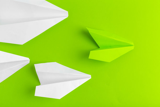 在绿色粉彩背景上的平面纸飞机图片下载