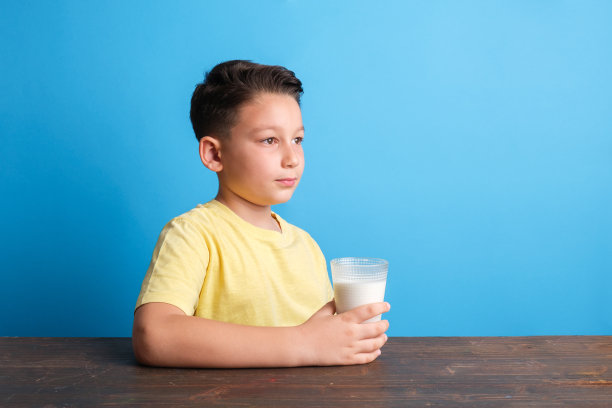 蓝色背景的孩子正在喝牛奶图片下载