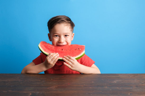 孩子在蓝色的背景上吃西瓜图片下载