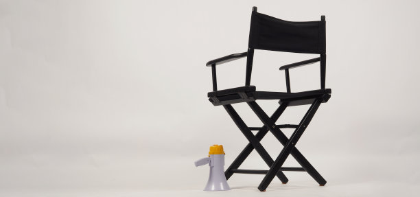 黑色导演椅的椅背和黄色扩音器放在白色背景的地板上。图片下载