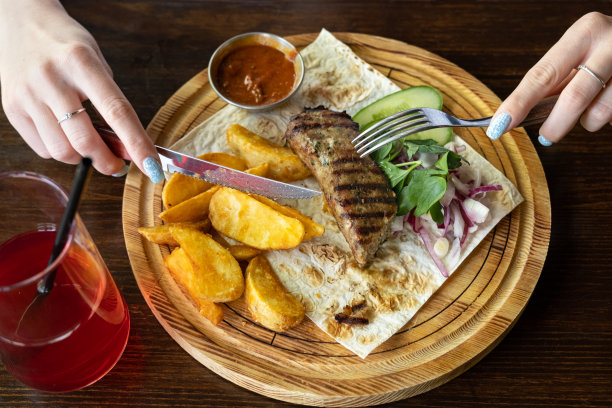 一个女人在餐厅里用木盘子吃烤肉串图片下载