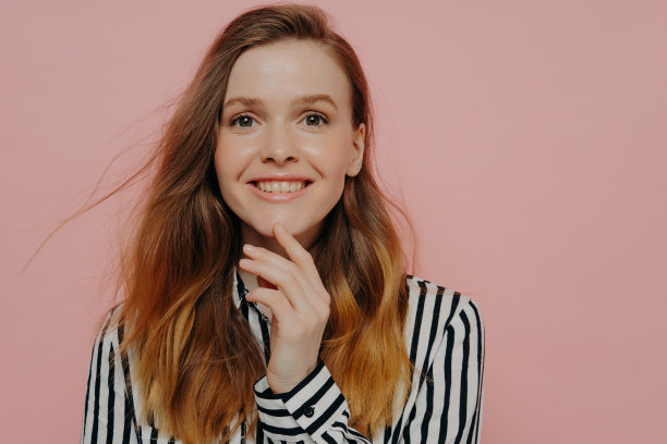 快乐的年轻女子在正式的衬衫微笑相机在工作室触摸下巴图片下载