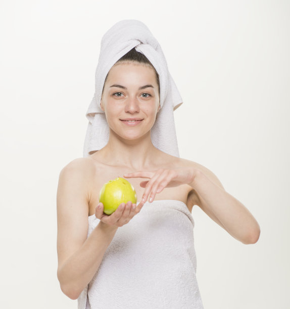 一幅美丽的肖像，一个开朗的女孩用毛巾在她的头上孤立。面部皮肤护理与健康理念。白底特写。女孩拿着杯子拿着苹果刷牙做面膜图片下载