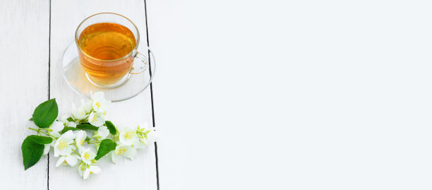 茉莉茶在一个木制的白色背景玻璃杯。杯用青茉莉花茶。横幅图片下载