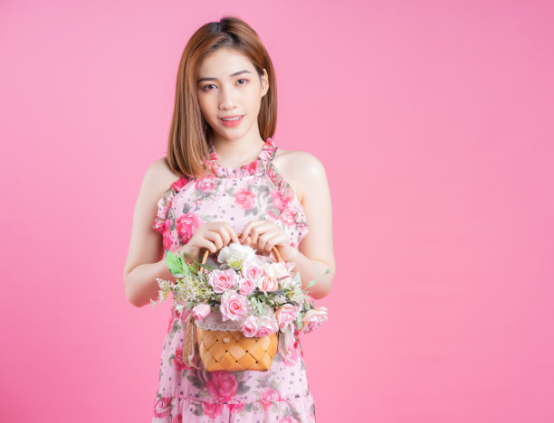 年轻的亚洲女孩在粉红色的背景下穿着花裙的照片图片下载