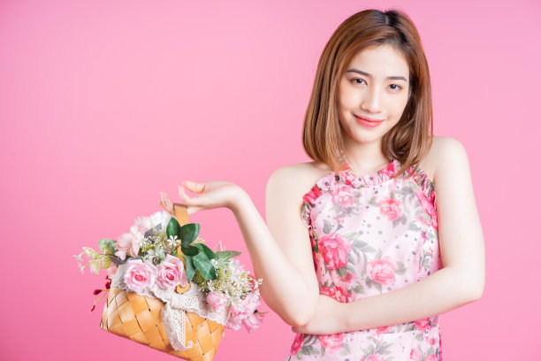 年轻的亚洲女孩在粉红色的背景下穿着花裙的照片图片下载