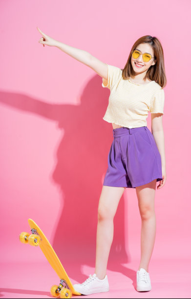 亚洲少女的照片与滑板在粉红色的背景图片下载