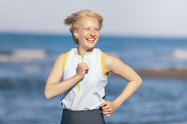 近距离的照片，美丽的微笑，开朗的运动女性跑步与风吹她的头发。图片下载