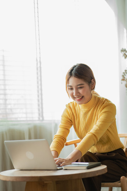 一个迷人的年轻亚洲女商人在她的办公桌上用笔记本电脑工作。垂直图图片下载