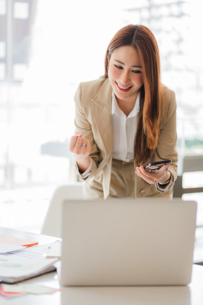 一名亚洲女商人用智能手机聊天的肖像。写在笔记本电脑笔记本电脑在家庭办公室，创业，商业，亚洲，女性，在线，中小企业，电话营销垂直画面图片下载