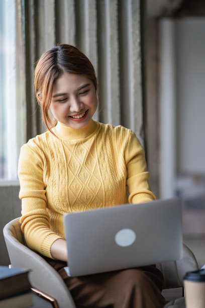 一个迷人的年轻亚洲女商人在她的办公桌上用笔记本电脑工作。垂直图图片下载