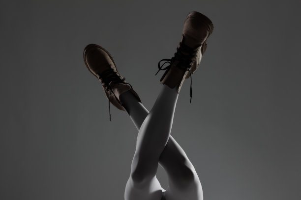 性感的女性腿部搭配白色打底裤和防水靴。侧面点燃一半剪影..图片下载