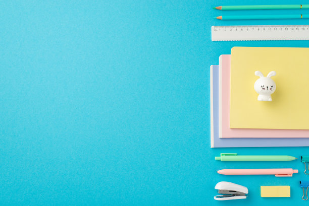 回到学校概念。订购组成文具计划兔形卷笔刀订书机笔橡皮尺活页夹和铅笔在孤立的蓝色背景与copyspace的俯视图照片图片下载