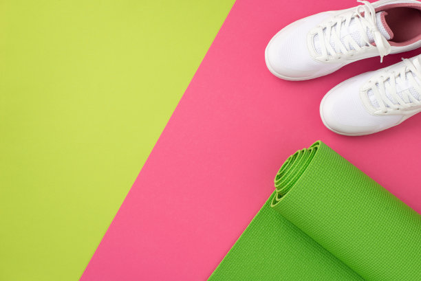 体育的概念。俯视图照片的运动垫和白色的鞋子在双色粉红色和绿色的背景与空白图片下载